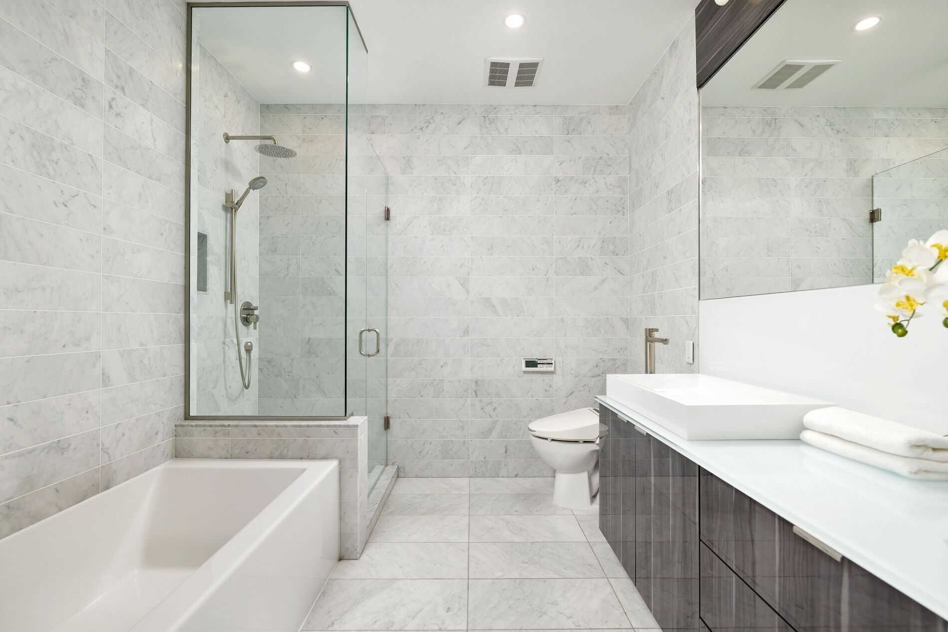 A modern bathroom with a glass-enclosed shower, a standalone bathtub, a toilet, and a vanity with a mirror.