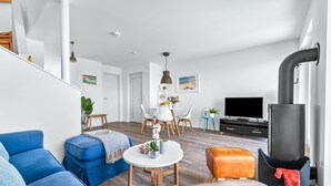 Un salon moderne avec un canapé bleu, une table basse ronde et un meuble TV sur lequel est posé un téléviseur à écran plat.