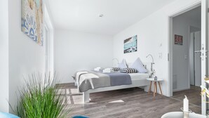 Une chambre à coucher moderne avec un lit, une table de chevet et une petite fenêtre.