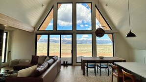 Een ruime woonkamer met een groot raam dat uitzicht biedt op een bergachtig landschap.