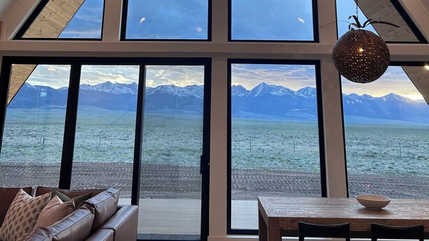 Een kamer met een groot raam met uitzicht op een bergachtig landschap.