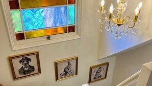 A staircase with a handrail, a stained glass window, and three framed pictures on the wall.