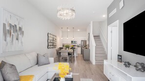A modern living room with a sofa, coffee table, and artwork on the wall. - Parkside Serenity by Avantstay Private Pool! (Davenport)