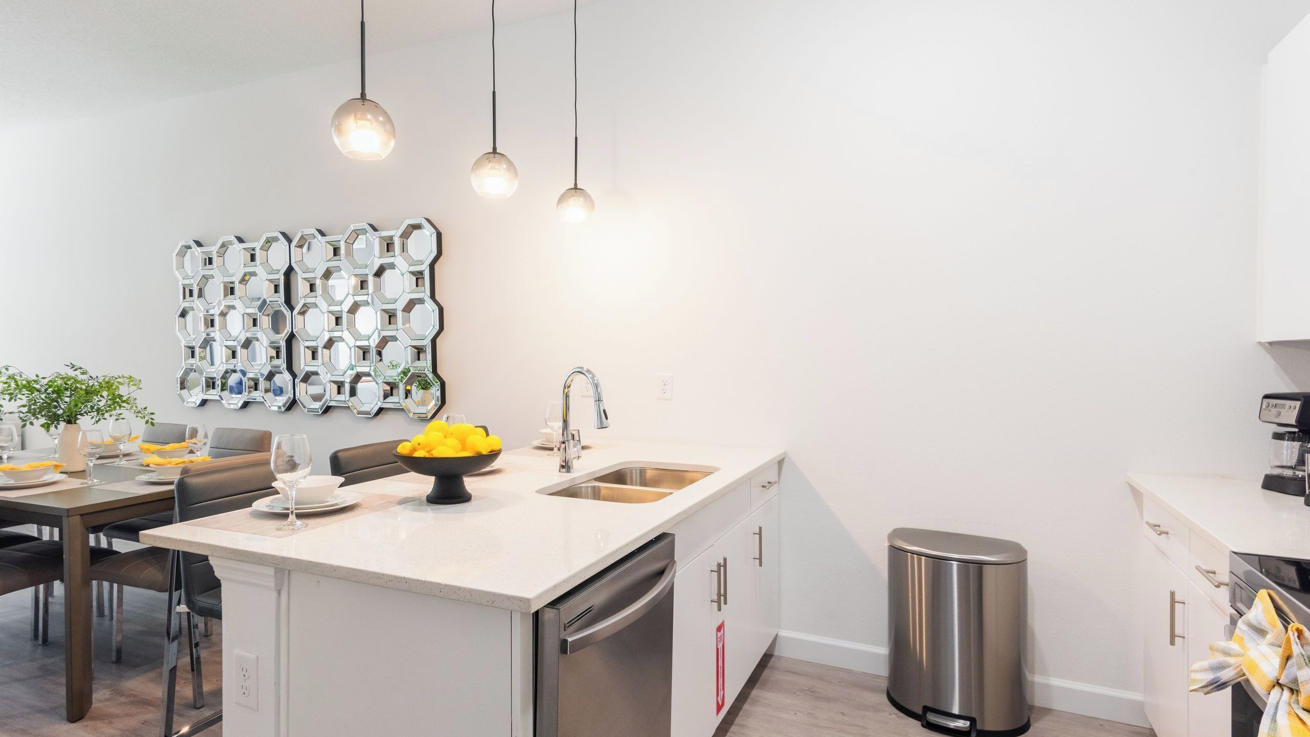 A modern kitchen with a central island, stainless steel appliances, and a decorative hexagonal mirror wall.