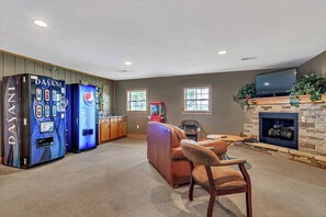 Ein Wohnzimmer mit Kamin, einer Ledersofa, einem Fernseher und Verkaufsautomaten.