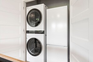 A front view of a laundry room with two stacked washing machines and a dryer. - New Home in Trophy Run with Private Hot Tub & Firepit, Near Taneycomo & Table Rock, Free Tickets (Branson)