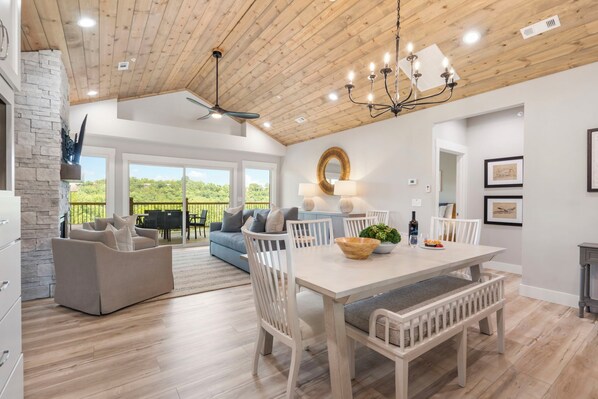 A spacious living area with a dining table, seating, and a view through large windows.