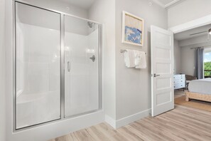 A bedroom with a glass-enclosed shower, a bed with a white headboard, and a painting on the wall. - New Home in Trophy Run with Private Hot Tub & Firepit, Near Taneycomo & Table Rock, Free Tickets (Branson)