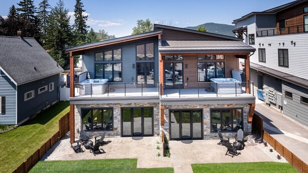 A two-story house with a patio area featuring outdoor seating and a barbecue grill. - New! Home Again Luxury Haven - Sleeps 8 (Whitefish)