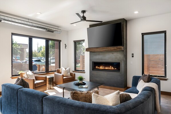 Una sala de estar moderna con chimenea, asientos cómodos y ventanas amplias.