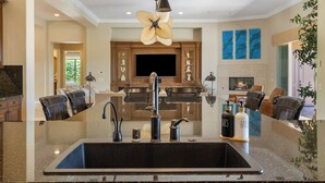 A modern kitchen with a central island, stainless steel appliances, and a ceiling fan. - Villa Paradiso - 2 Pools, 5 Suites & More! (Indio)