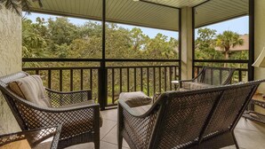 A covered balcony with wicker furniture and a ceiling fan. - Condo in Bonita! 2 Miles to the Beach! Beach Shuttle Included! (Bonita Springs)