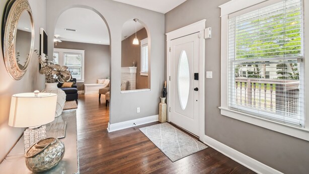 A modern hallway with a wooden floor, a large mirror, and a chandelier.