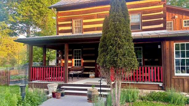 A log cabin with a porch, a tall tree in front, and a pathway leading to the entrance. - Spacious In-Town Retreat (Lewisburg)