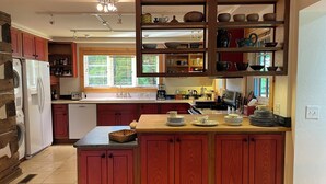 A kitchen with wooden cabinets, a central island, and a built-in shelving unit above the island. - Spacious In-Town Retreat (Lewisburg)