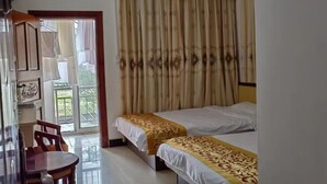 A room with two beds, a wooden chair, a table, and a view of a balcony. - Dongxing Wanwei Jintan Xiangyue Hotel (Dongxing)