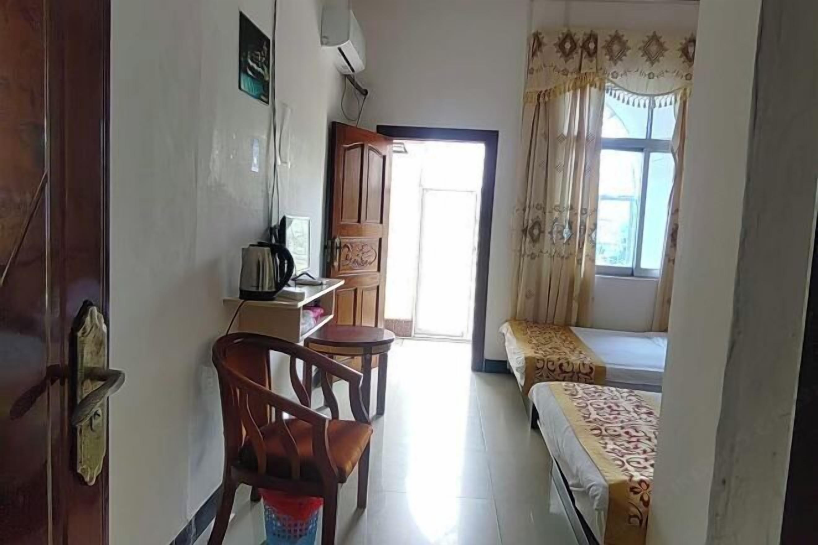 A room with a bed, a desk with a chair, a window with curtains, and a door.