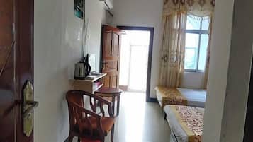 A room with a bed, a desk with a chair, a window with curtains, and a door.