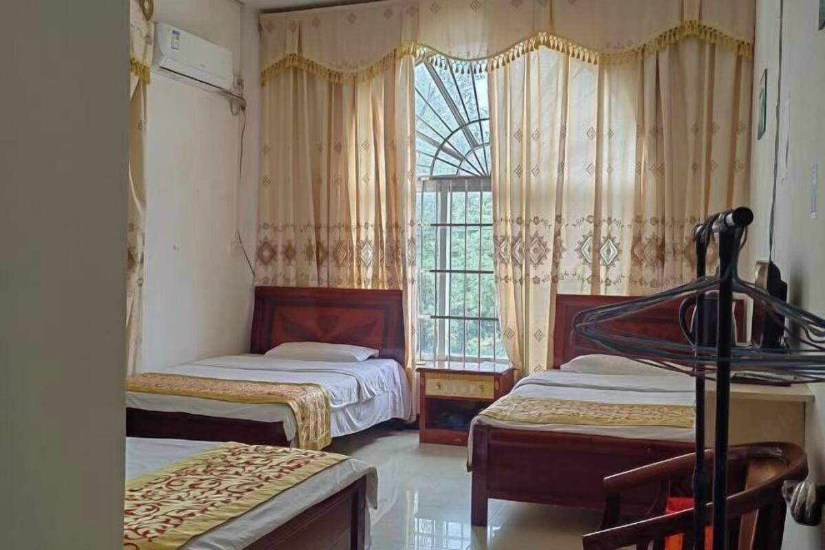 A room with two beds, a window with curtains, a chair, and a desk.