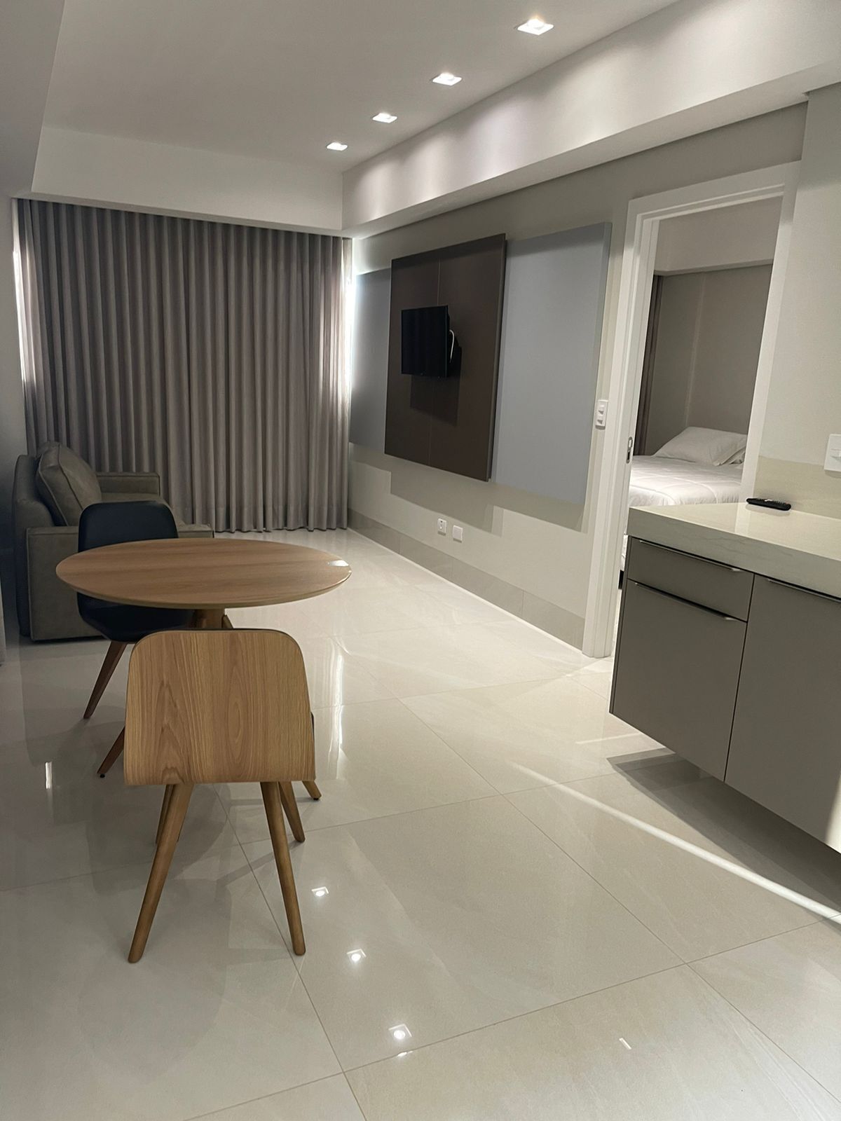 Een moderne hotelkamer met een zithoek, een bank, een aan de muur bevestigde televisie en een keukenblad.