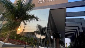 The Riva Apart Hotel facade with a modern design, palm trees, and a clear sky. - Riva Apart Hotel (Campo Mourao)