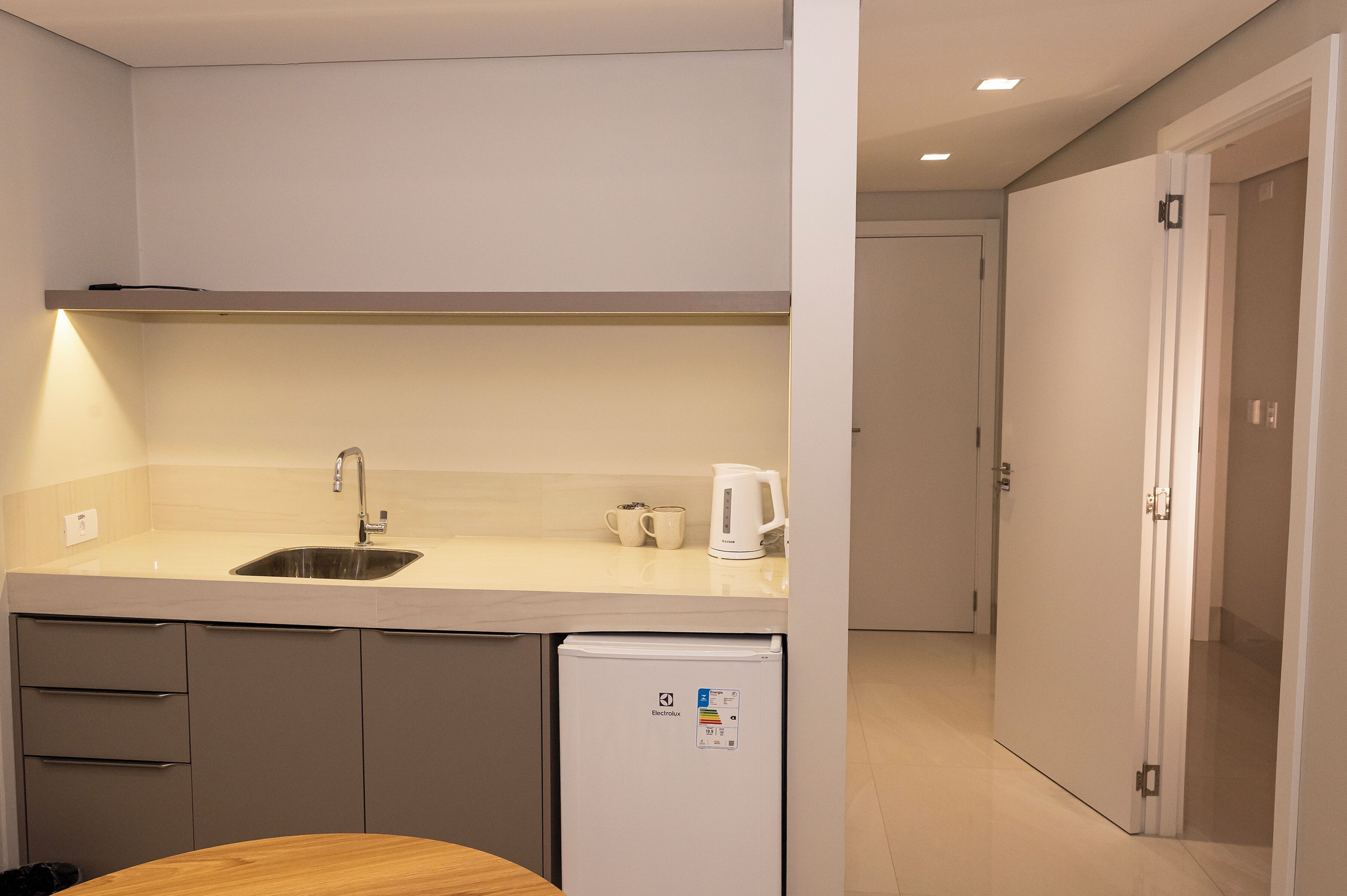 A compact kitchen with a sink, a coffee maker, and a small refrigerator.