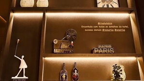 A wall with shelves displaying various items including a clock, bottles, and decorative objects. - Riva Apart Hotel (Campo Mourao)