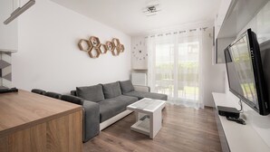Ein modernes Wohnzimmer mit grauem Sofa, einem Holztisch und einem Flachbildfernseher.