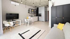 Ein modernes Wohnzimmer mit Flachbildfernseher, Essbereich und Küche.