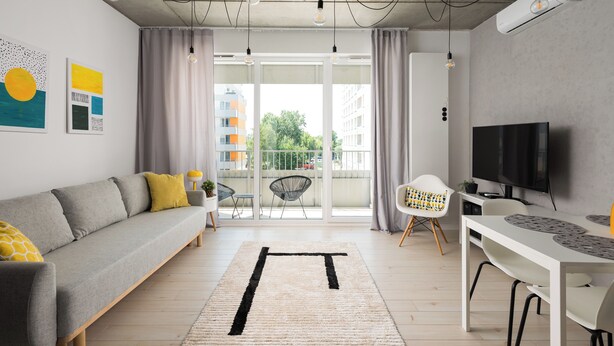 Ein modernes Wohnzimmer mit einer Couch, einem Esstisch und einem Fernseher.