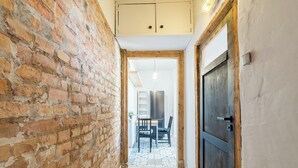 A narrow hallway with exposed brick walls, a wooden door, and a tiled floor. - Głogowska Spacious Apartment (Poznań)