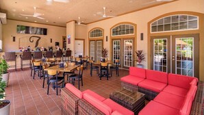 A spacious indoor area with multiple dining tables and chairs, a red sofa, ceiling fans, and large windows. - Remodeled 3 bed / 2 bath near Disney (Davenport)