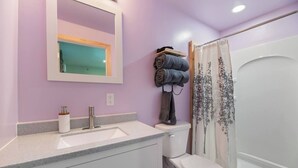 Un baño con lavamanos, espejo, inodoro y cortina de ducha.