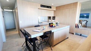 Una cocina moderna con una isla central, sillas negras, una mesa de comedor y un horno empotrado.