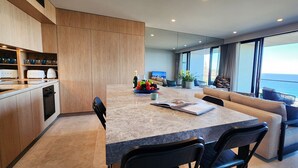 Una cocina moderna con encimera de mármol, armarios de madera y un comedor con vistas al océano.