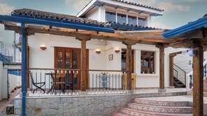 A traditional building with a tiled roof, wooden beams, and a stone staircase leading to a wooden door. - Suite de Lujo en Casa Patrimonial Reformada, en Zona Céntrica (Cuenca)
