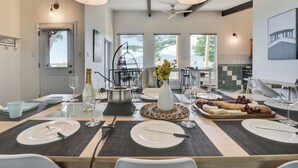 Comedor con una mesa grande dispuesta para una comida, una silla colgante y vistas al exterior.