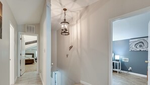 En gang med trappe op til et soveværelse, en dekorativ lampe og en væg med spiralmønster.