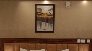 Ein Hotelzimmer mit einem großen Bett, zwei Nachttischlampen, einem gerahmten Kunstwerk an der Wand und einem Holz-Kopfteil.