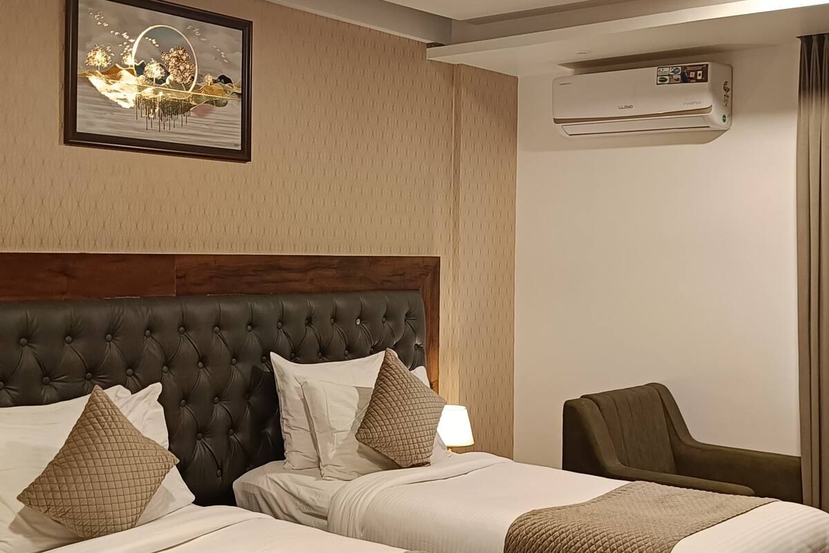 Hotelkamer met een groot bed, een klein bed, een bureau, een plafondventilator, een airconditioning en een ingelijste foto aan de muur.