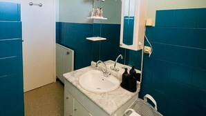 Ein Badezimmer mit einem weißen Waschbecken, einem Spiegel darüber und einem Handtuchhalter.
