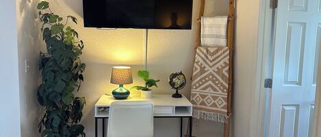 Un pequeño espacio de oficina con escritorio, silla, lámpara, planta en maceta, globo terráqueo y una escalera apoyada en la pared.