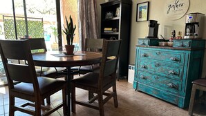 A dining area with a round table, four chairs, a potted plant, a bookshelf, a coffee machine, and a teal dresser. - 2bd/2ba 1st fl condo Sabino Canyon in Tucson w king/queen pool, pickleball, pets (Tucson)
