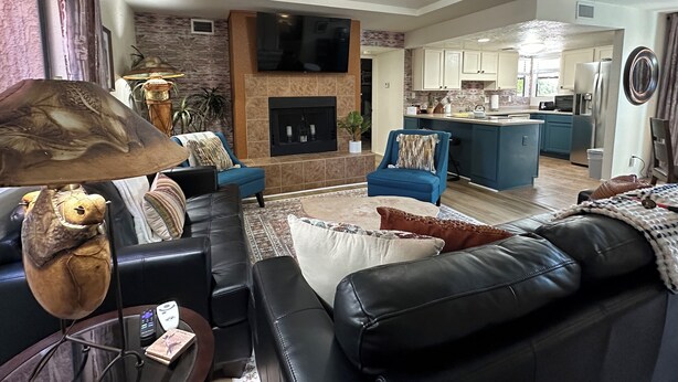 A modern living room with a fireplace, a ceiling fan, and a kitchen in the background. - 2bd/2ba 1st fl condo Sabino Canyon in Tucson w king/queen pool, pickleball, pets (Tucson)
