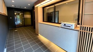 A hallway with a tiled floor, a reception desk with a phone, and a window with blinds. - Hiz Hotel Gion-Shirakawa (Kyoto)