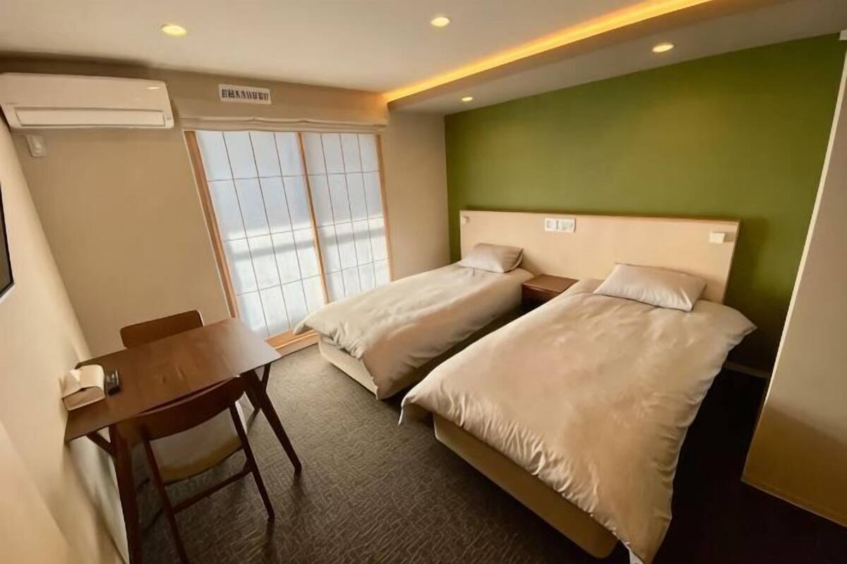 Ein Hotelzimmer mit zwei Betten, einem Schreibtisch und einem Stuhl.
