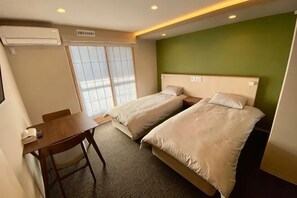 Une chambre d’hôtel avec deux lits, un bureau et une chaise.