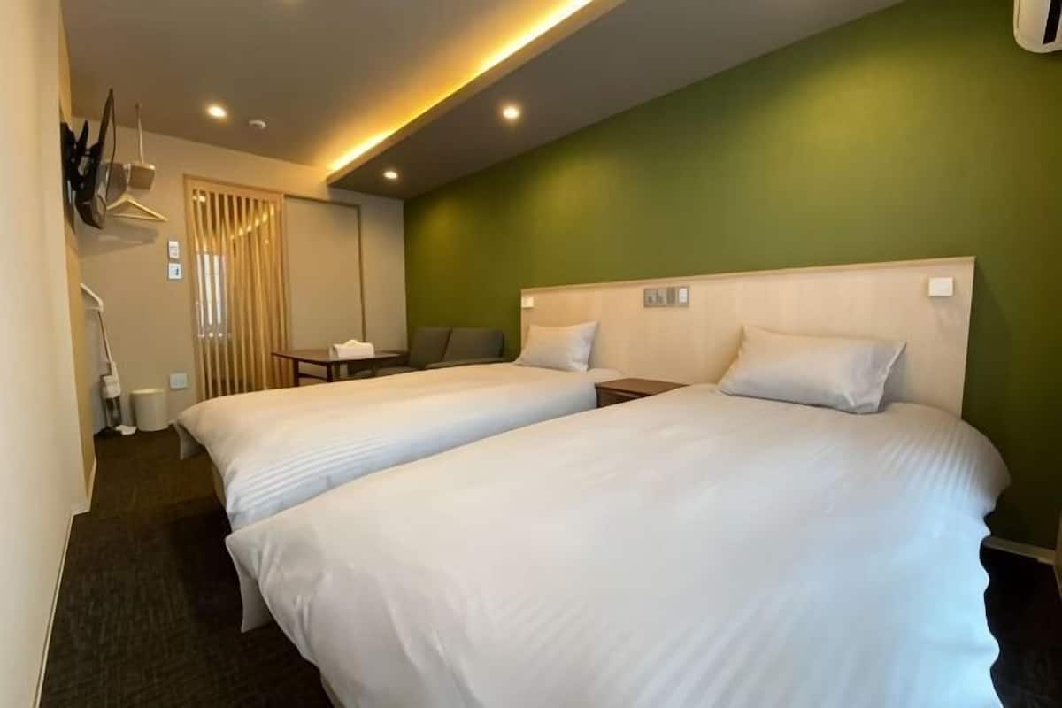 A hotel room with two beds, a desk, and a chair.
