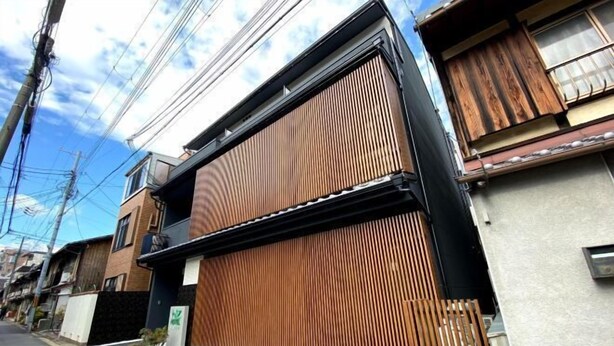 A residential building with a large wooden sliding door, a visible garage door, and a clear sky. - Hiz Hotel Gion-Shirakawa (Kyoto)