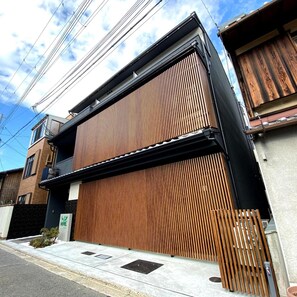 A modern building with a large wooden slatted facade, a visible entrance, and a clear sky.